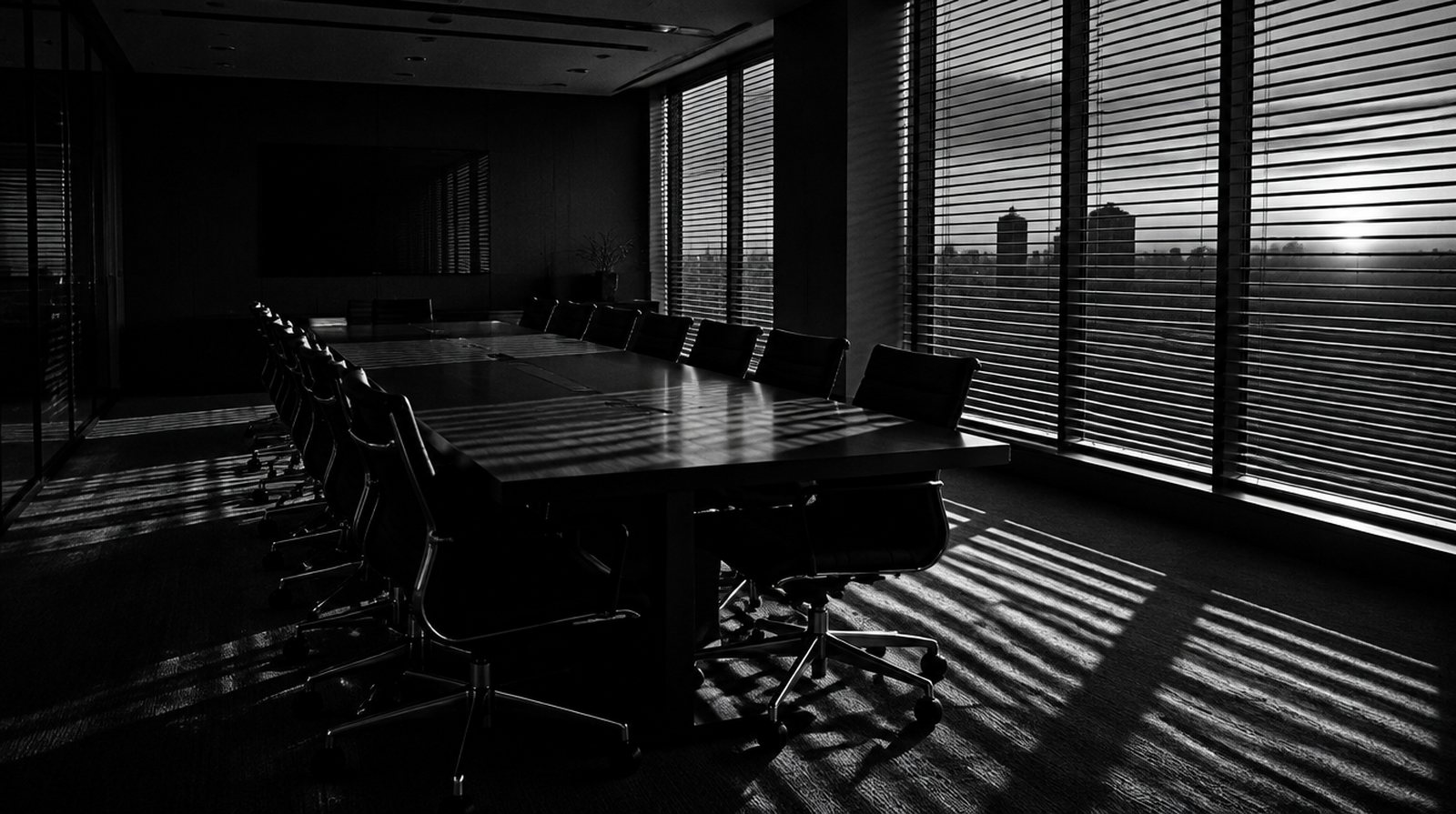 KI-generierte Darstellung: leerer Konferenzraum in der Dämmerung, Stühle an den Tisch geschoben