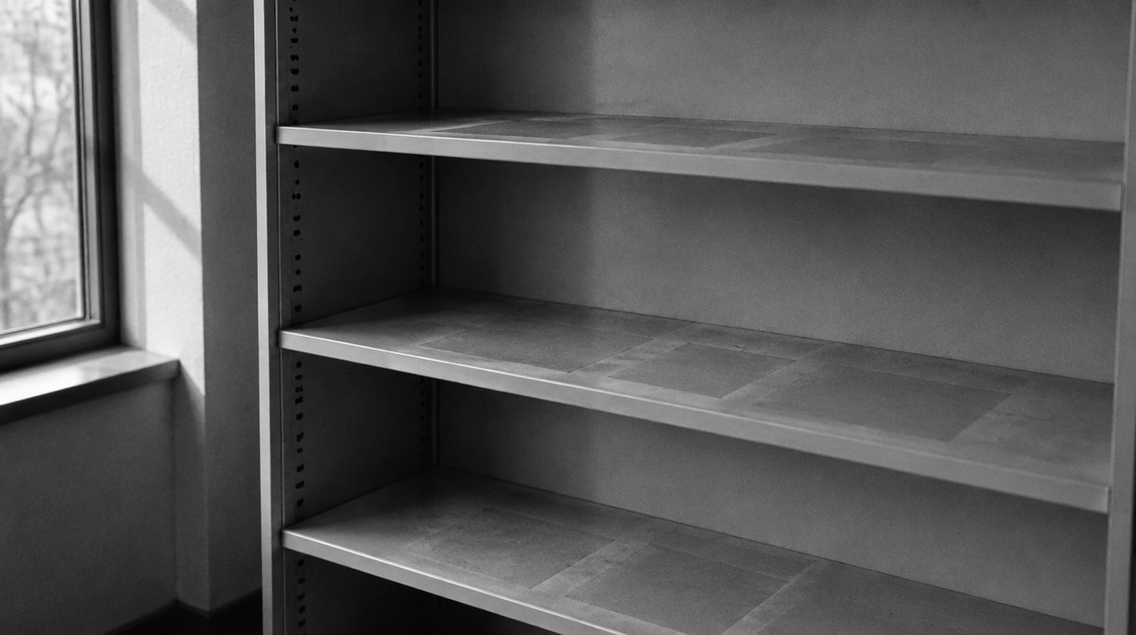 KI-generierte Darstellung: leeres Büroregal mit schwachen Staubspuren, wo Kisten standen