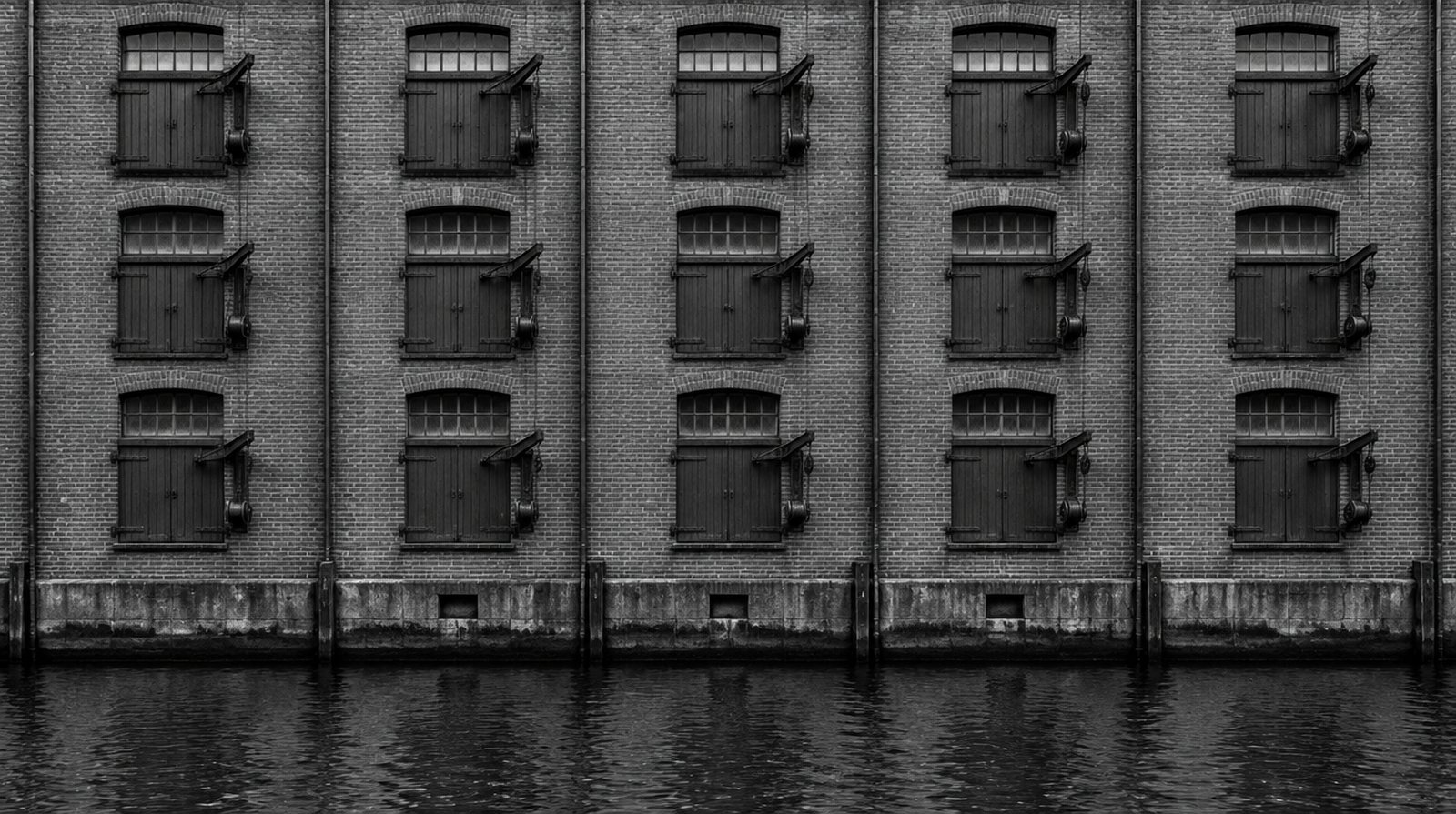KI-generierte Darstellung: Ziegelwand eines Speichers am Kanal, Reihen gleicher Ladeluken