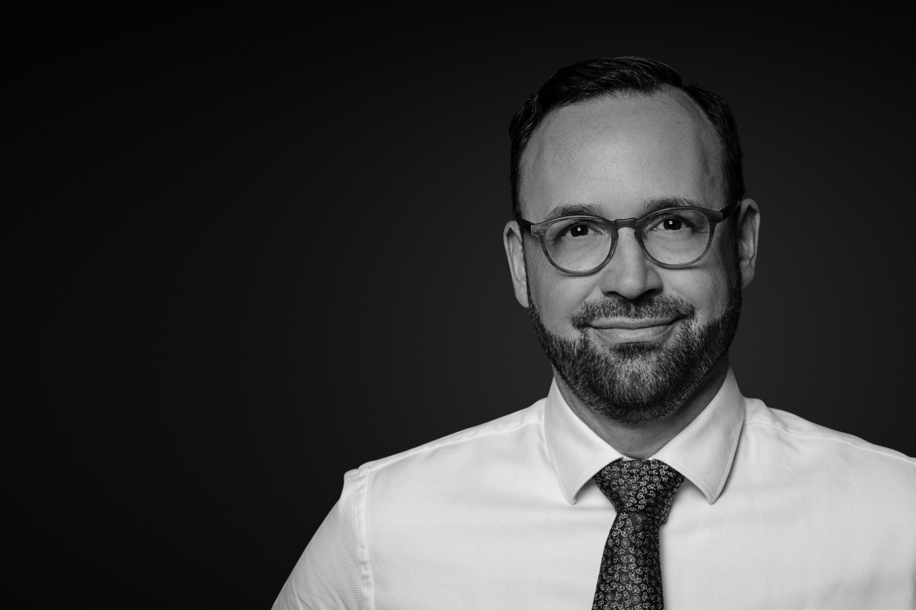 Rechtsanwalt Andrija Maximilian Pancic, Schwarzweißaufnahme vor dunklem Studiogrund, Hemd und Krawatte, Blick in die Kamera